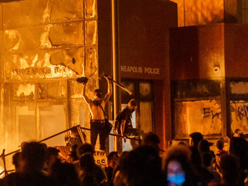 Flames from a nearby fire illuminate protesters standing on a barricade in front of the Third Police Precinct on May 28, 2020 in Minneapolis, Minnesota.
