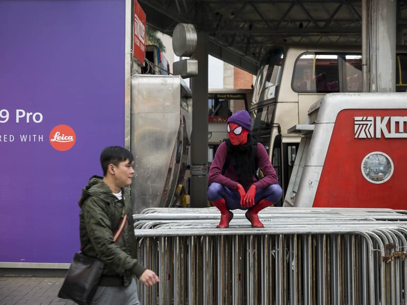 A man (C) wearing a Spiderman costume crouches on top of barricades in the Tsim Sha Tsui district of Hong Kong on Dec 29, 2016. Photo: AFP