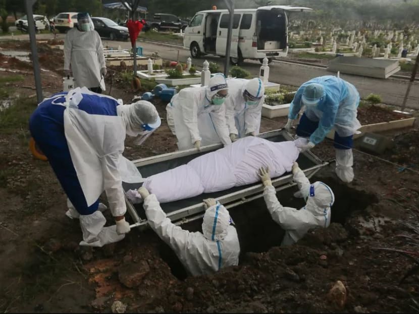 Workers and family members wearing protective suits bury a victim of the Covid-19 disease at a cemetery in Shah Alam Tuesday, May 18, 2021.