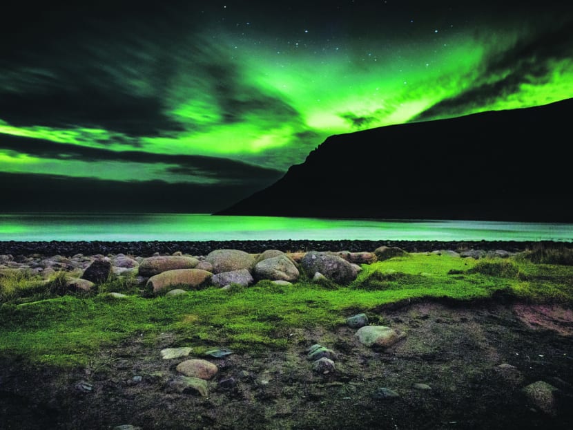 The Northern Lights colour the sky beyond the Norwegian Sea’s shoreline in Unstad, Norway. 
Photo: The New York Times