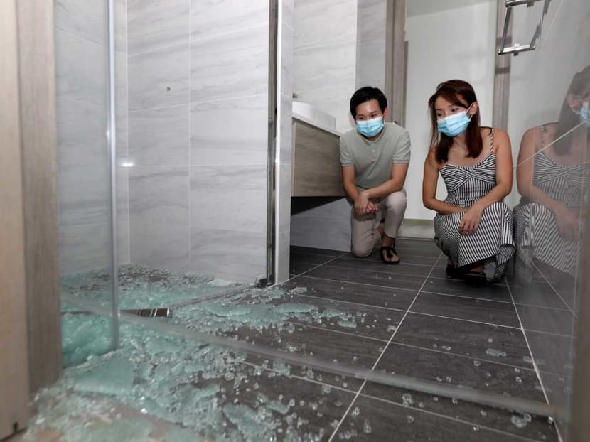 Siblings Mr Edward Quek, 31, and Ms Janelle Quek, 35, with a bathroom door which they say shattered and collapsed for no apparent reason.