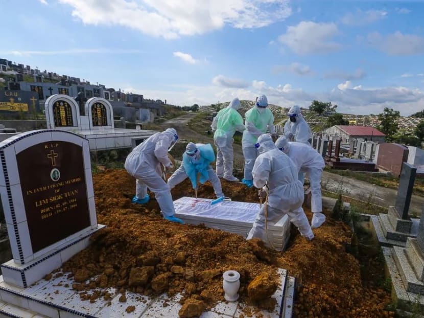 Workers wearing personal protective equipment bury a person who died from Covid-19 at the Meru Christian Cemetery in Klang, on Monday, Aug 9, 2021.
