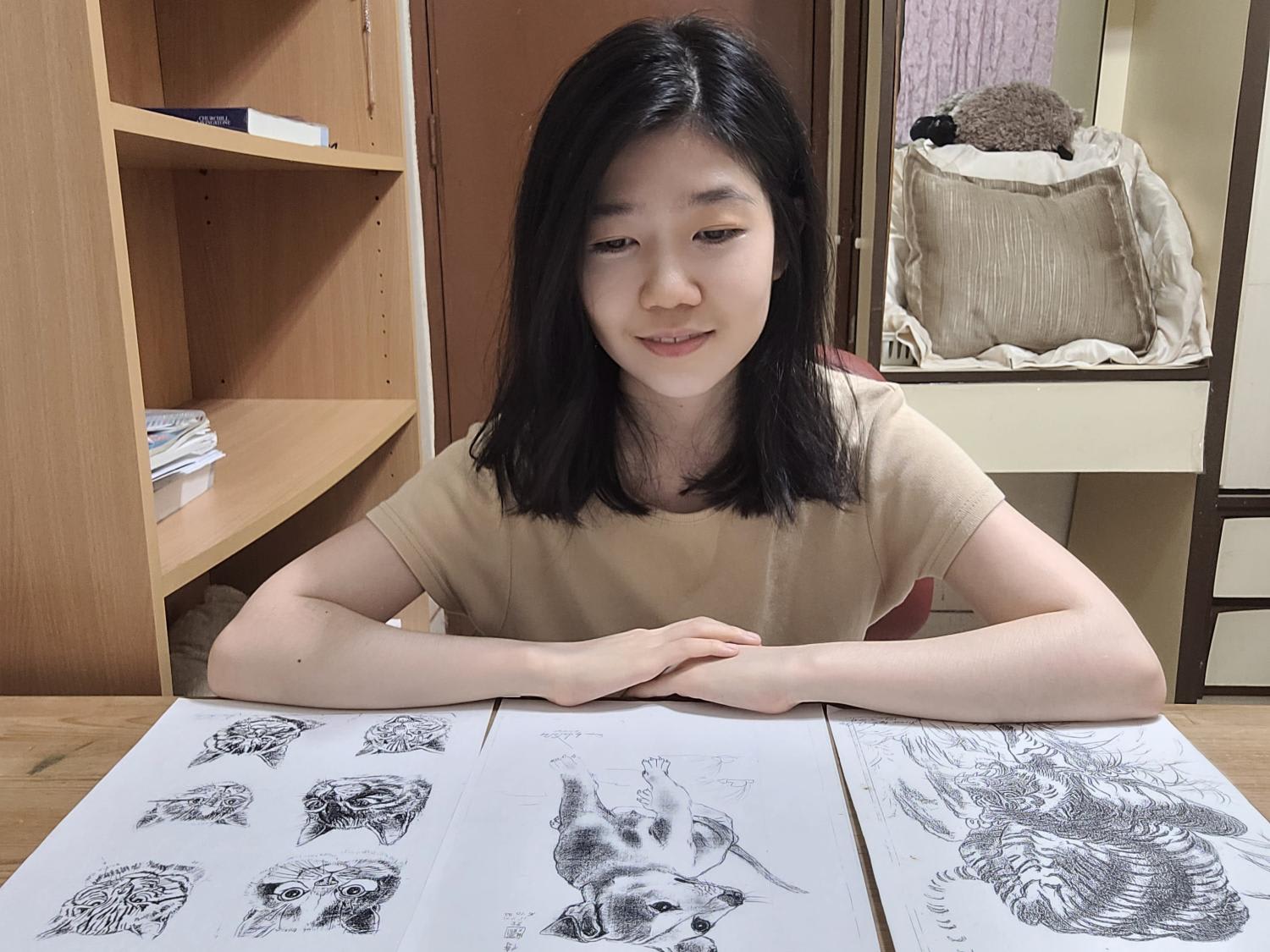 The author is seen here with photocopies of the drawings made by a janitor from her primary school which she has kept. The author is seen here with photocopies of the drawings made by a janitor from her primary school which she has kept.