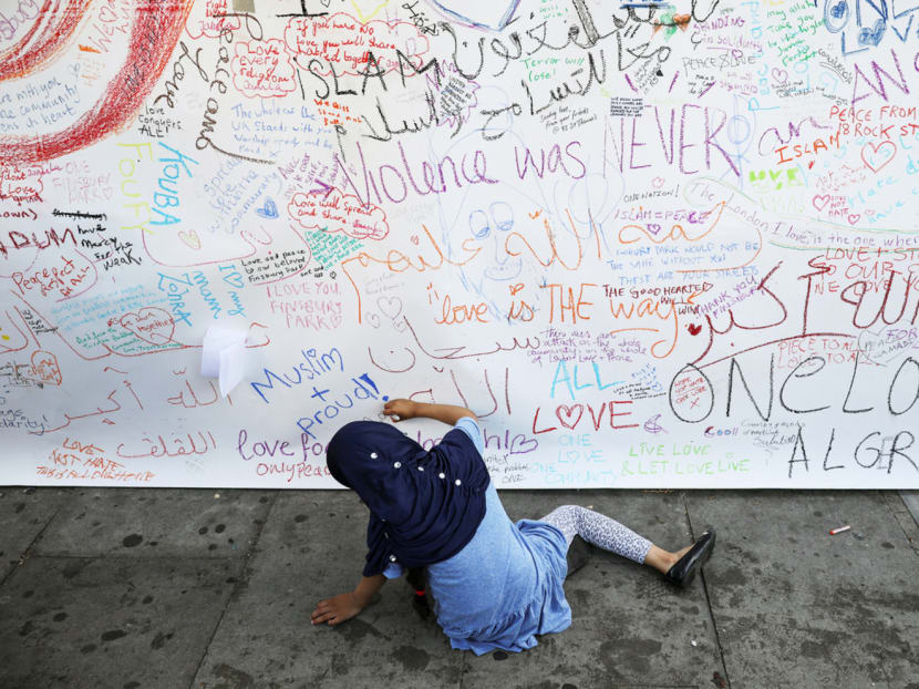A girl writing a tribute note on Tuesday during a vigil near to where a van was driven into a group of Muslims in Finsbury Park, North London, on Monday. Photo: Reuters