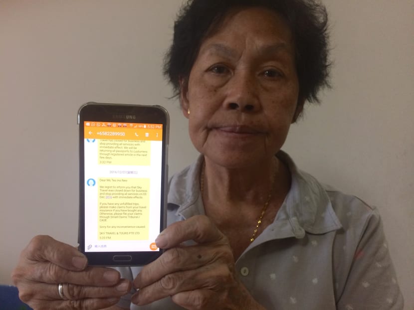 Mdm Teo Ino Neo, 68, holding up the SMS she received on Dec 5, 2016, the day that she was supposed to depart for a trip to Hokkaido, that the travel agency she had booked her trip on had closed down. Photo: Cynthia Choo/TODAY