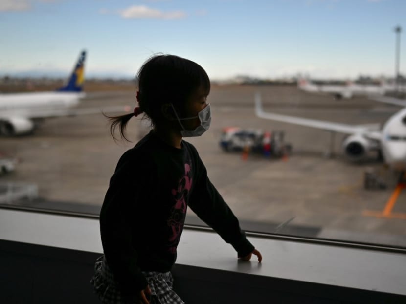 A child wearing a protective face mask looks on from the departure terminal of Tokyo's Haneda airport.