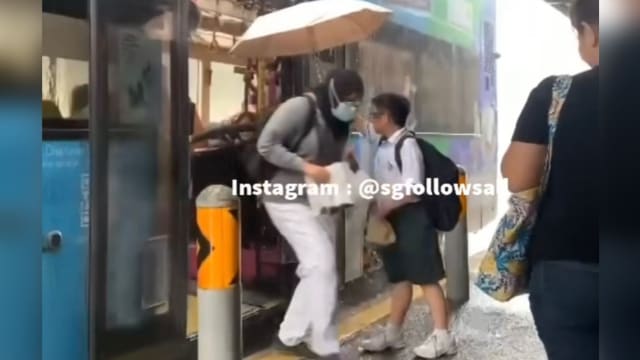 中一男童巴士车站撑伞为乘客挡雨 网民：非常有教养