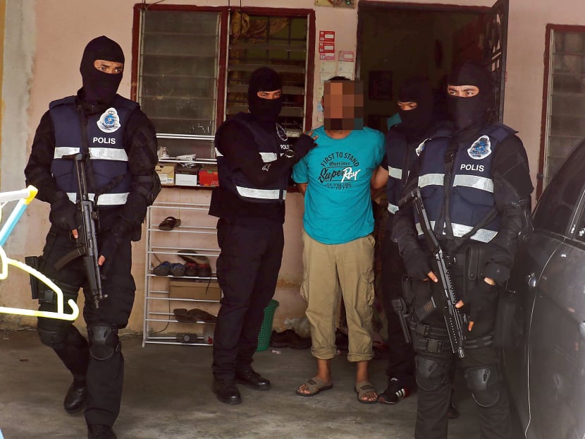 Malaysian police officers with a suspected Islamic State militant. Photo: Royal Malaysian Police Malaysian police officers with a suspected Islamic State militant. Photo: Royal Malaysian Police