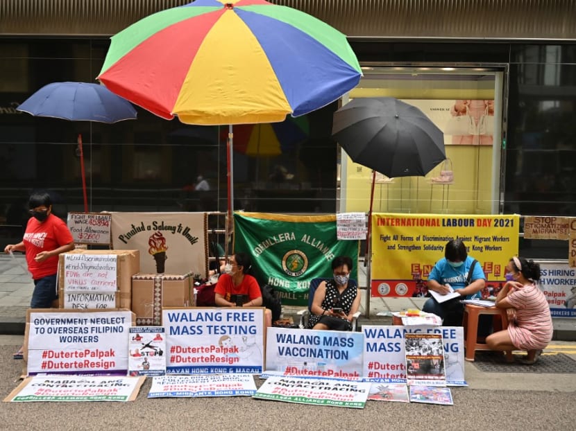 Migrant workers sit in front of protest banners in the Central district of Hong Kong on May 1, 2021, after the government said they were planning to roll out mandatory Covid-19 vaccinations for the city's 370,000 domestic workers.