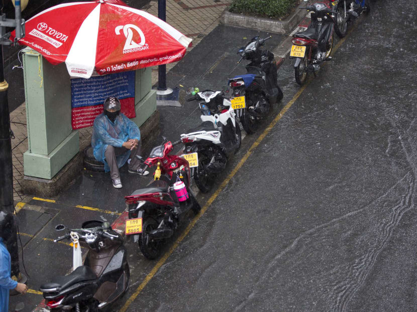 A motorcycle taxi-rider resting during a downpour in Bangkok, Thailand, on May 30, 2017. Photo: AP