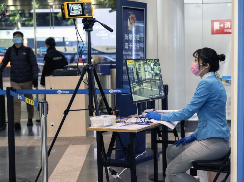 An employee waits to check passengers for fever at an entrance to a terminal at Beijing Capital International Airport on Feb. 9, 2020.