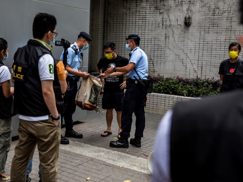 Police search the bag of pro-democracy activist Raphael Wong (C), from the League of Social Democrats, during a protest in Hong Kong on July 1, 2021, while a flag-raising ceremony to mark the 24th anniversary of Hong Kong's handover from Britain is held near by.