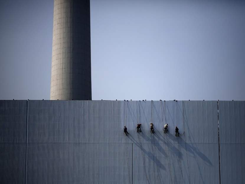 Workers paint an exterior wall of a power plant in Beijing. Reuters file photo