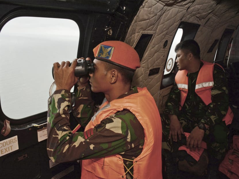A crewmember of an Indonesian Air Force Super Puma  helicopter of 6th Air Squadron uses a binocular to scan the horizon during a search operation for the victims of AirAsia Flight QZ 8501. Photo: AP