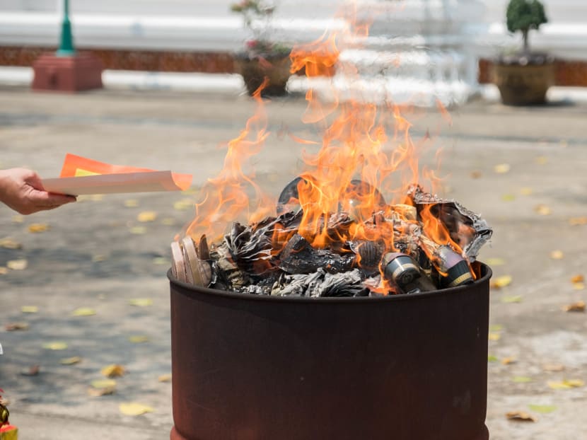 Joss paper being burnt in a metal container.
