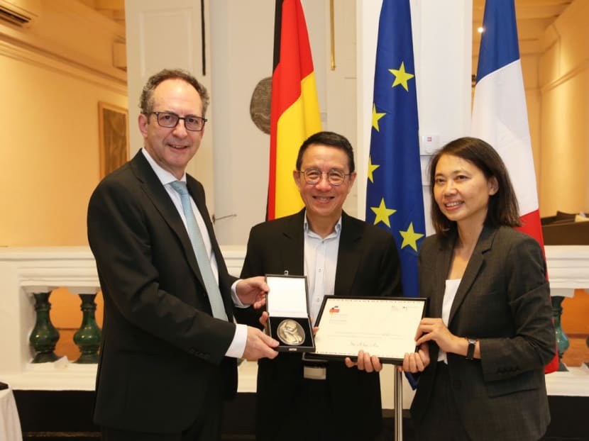 Mr Alex Au receiving the Franco-German Human Rights and Rule of Law Prize from Germany's ambassador to Singapore Dr Norbert Riedel (left), and France's ambassador to Singapore, Ms Minh-di Tang on Jan 13, 2023. 