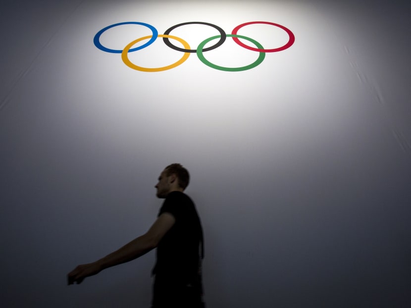 A man walks under the Olympic logo during the 128th International Olympic Committee (IOC) session in Kuala Lumpur, Malaysia on Sunday, Aug 2, 2015. Photo: AP