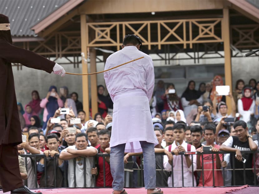 A Sharia law official whips a man convicted of adultery with a rattan cane in Banda Aceh, Indonesia, when two men each face up to 100 stroke of the cane after neighbors reported them to Islamic religious police for having gay sex. Photo: AP