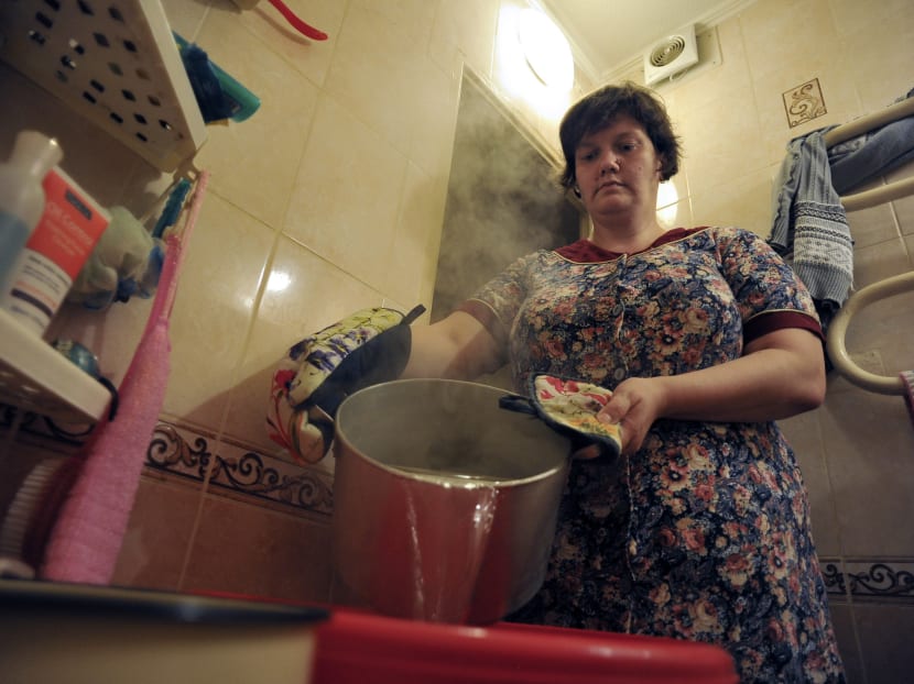 A woman preparing hot water to wash her hair, in her apartment in Saint Petersburg, Russia, July 7, 2016. Photo: AFP