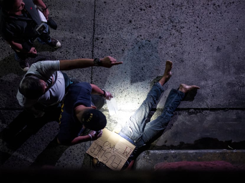 Police officers investigate the body of an alleged drug dealer, his face covered with packing tape and a placard reading "I'm a pusher", on a street in Manila, July 8, 2016. Photo: AFP