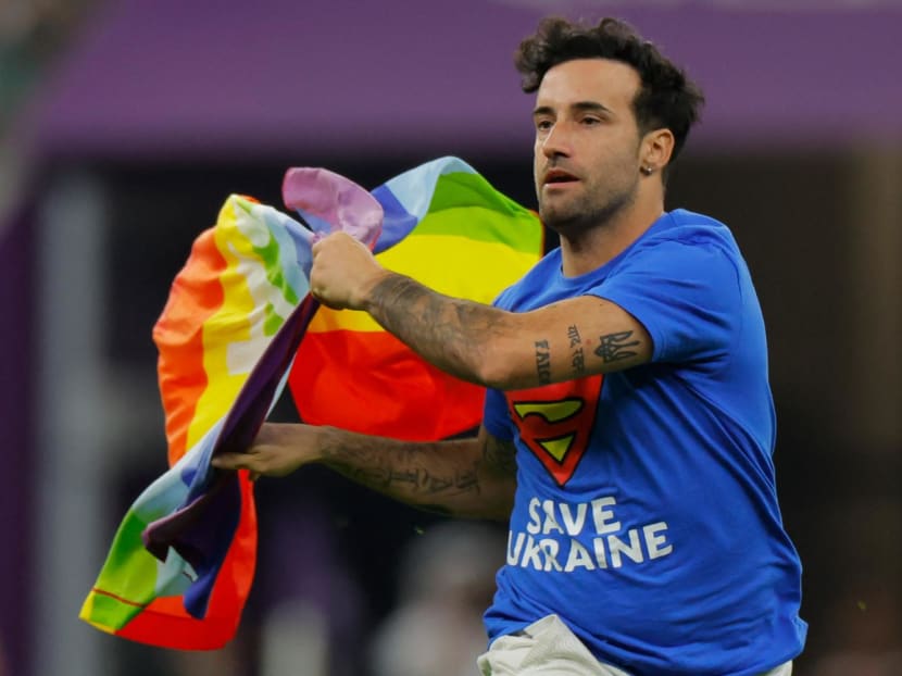 A man wearing a t-shirt reading "Save Ukraine" runs on the pitch waving a rainbow LGBT flag on the pitch during the Qatar 2022 World Cup Group H football match between Portugal and Uruguay at the Lusail Stadium in Lusail, north of Doha on Nov 28, 2022.