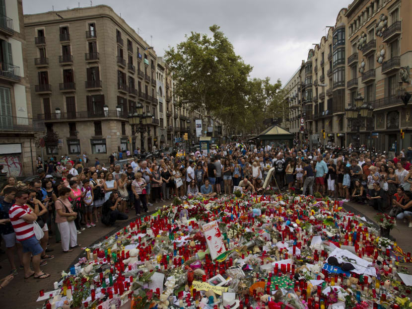 People pay respect at a memorial tribute of flowers, messages and candles to the victims on Barcelona's historic Las Ramblas promenade on the Joan Miro mosaic, embedded in the pavement where the van stopped after killing at least 13 people in Barcelona, Spain. Photo: AP