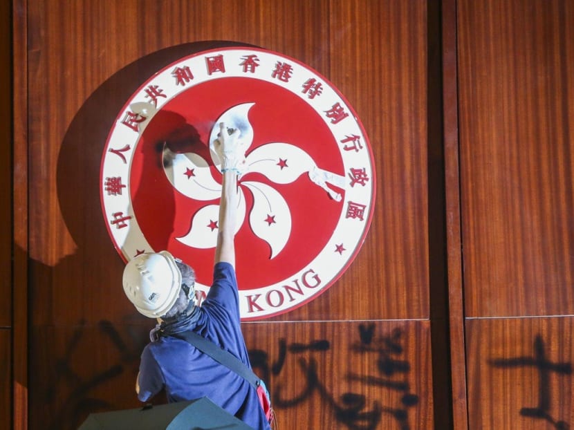 A protester spray-paints the Hong Kong emblem inside the Hong Kong Legislative Council chamber.