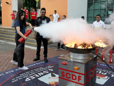 Writer Eveline Gan putting out a fire during a hands-on training session under the Community Emergency Preparedness Programme on May 5, 2023. 