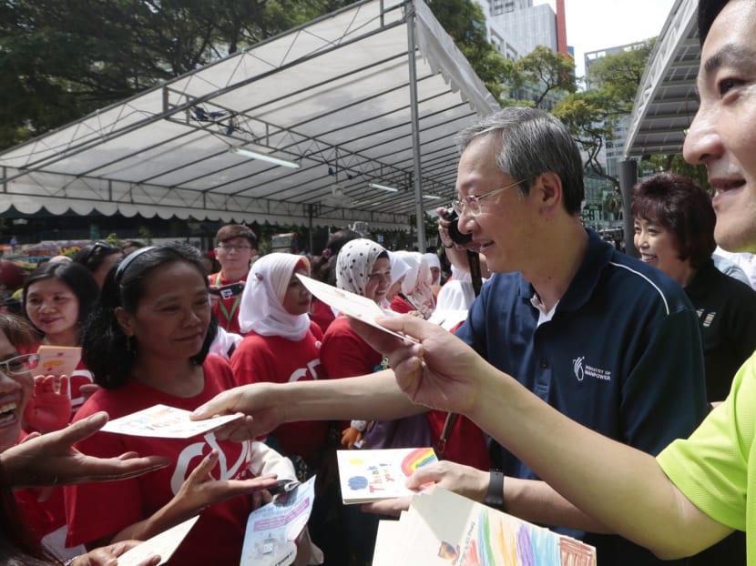 Mr Tan (in blue) giving out appreciation cards, made by primary school students, to foreign domestic workers during a May Day celebration event yesterday. Photo: Jason Quah