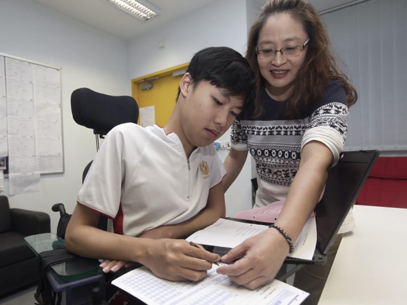 Madam June Yeo, 52, an allied educator for learning and behavioural support at Montfort Secondary School, helps 15-year-old Ansel Lim, who suffers from a muscular disorder, with his school work. Photo: Ernest Chua