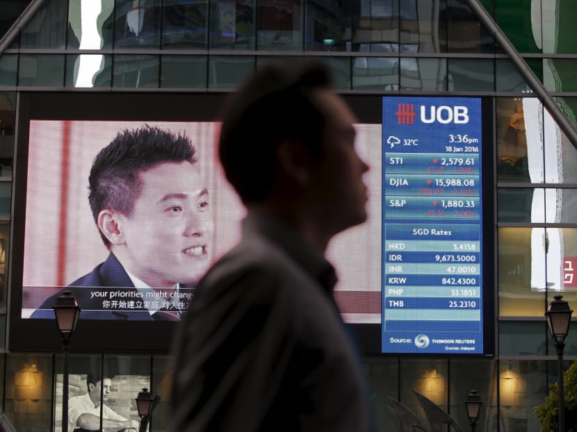 A man passes a board showing the decline of Straits Times Index, Dow Jones Industrial Average and the Standard and Poor's index at the central business district in Singapore on Jan 18, 2016. Photo: Reuters