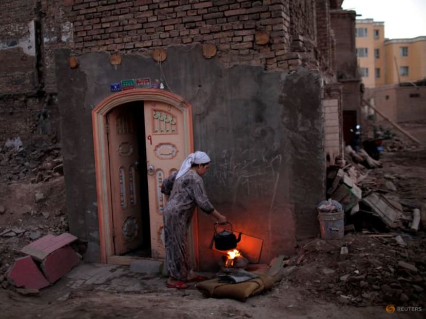 FILE PHOTO: A woman cooks in her house next to the remnants of other houses, demolished as part of a building renovation campaign in the old district of Kashgar, in Xinjiang province August 3, 2011. Picture taken August 3, 2011. REUTERS/Carlos Barria