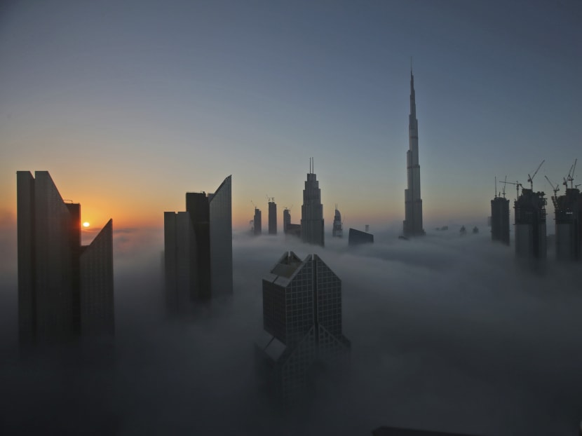 The sun rises over the city skyline with the Burj Khalifa, world's tallest building at the backdrop, seen from a balcony on the 42nd floor of a hotel on a foggy day in Dubai, United Arab Emirates, Saturday, Dec 31, 2016. Photo: AP