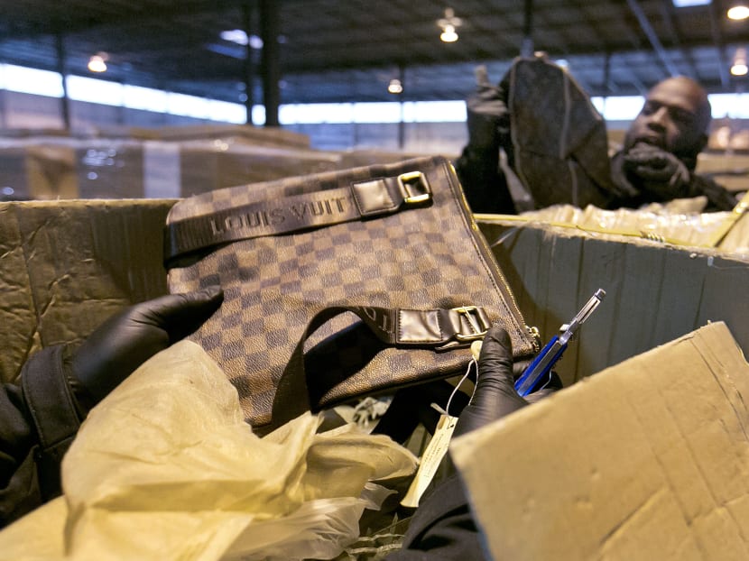 In this Oct 28, 2015, photo, counterfeit Louis Vuitton bags are found in a shipment by US Customs and Border Protection officers, including Mr Gabriel Richardson, right, at H&M Terminals Transport warehouse, in Kearney, New Jersey. Photo: AP