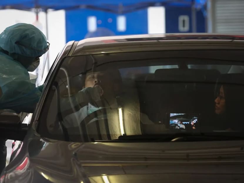A health worker in a protective suit collects a swab sample from a motorist at a drive-through testing site for Covid-19 at MSU Medical Centre in Shah Alam.