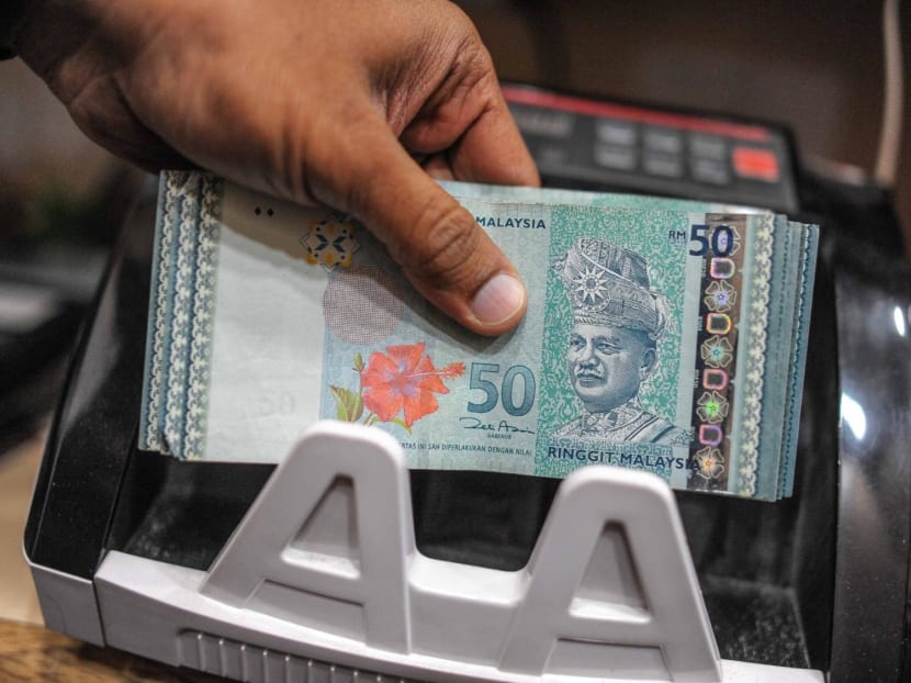 A money changer counting Malaysian ringgit banknotes. 