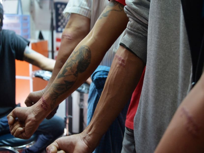 In this photo taken on Feb 6, 2021, men show their new tattoos that read "Kabar Makya Bu" or "we fight until the world end" in protest over the Myanmar military coup at a tattoo parlour in Naypyidaw.