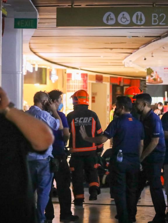 Police and firefighters seen at the second basement level of VivoCity mall, where a fire led to workers from about a dozen shops and food stalls being evacuated on June 7, 2022. 