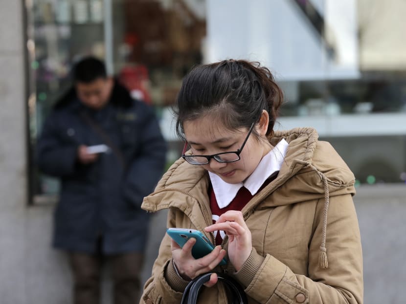 Chinese people check on their smartphones on a street in Beijing today, Feb 16, 2015. On the Internet, in college classrooms and in corporate offices, the Chinese Communist Party has raised the virtual wall separating the world’s most populous country from the rest of the globe. Photo: AP