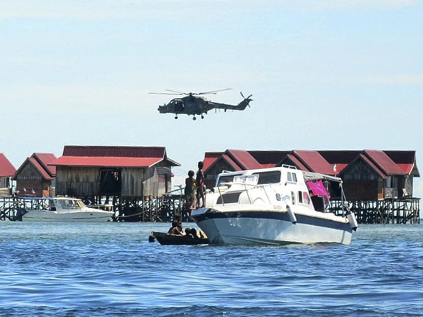 A police helicopter patrols near Mabul Water Bungalows Resort where a Malaysian policeman was killed and another is missing after they were ambushed late Saturday by a group of masked gunmen, in Mabul Island, Sabah state on Borneo, Malaysia, July 13, 2014. Photo: AP