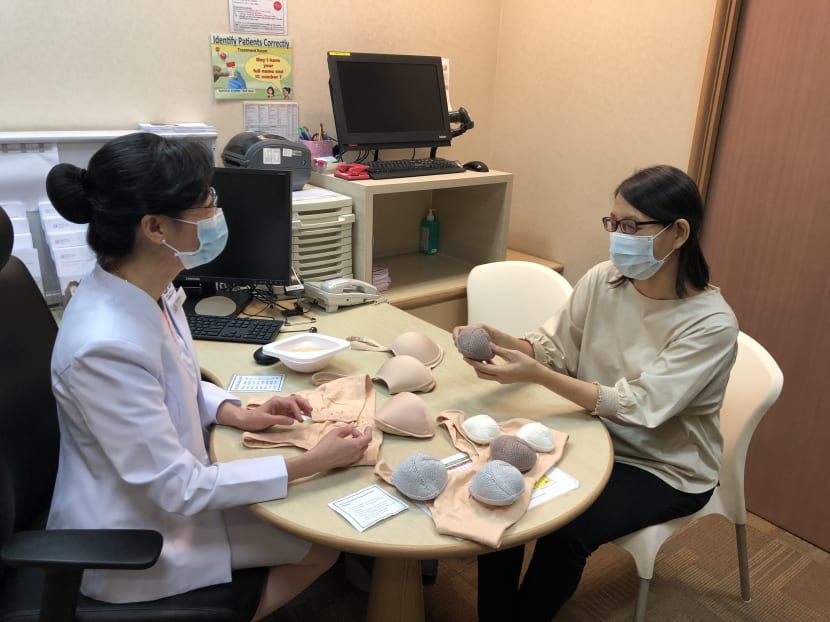 Ms Teresa Ng (left) from KK Women's and Children's Hospital explaining the use of cotton hand-knitted breast prostheses and commercially manufactured breast prostheses to cancer survivor Ng Sock Peng.