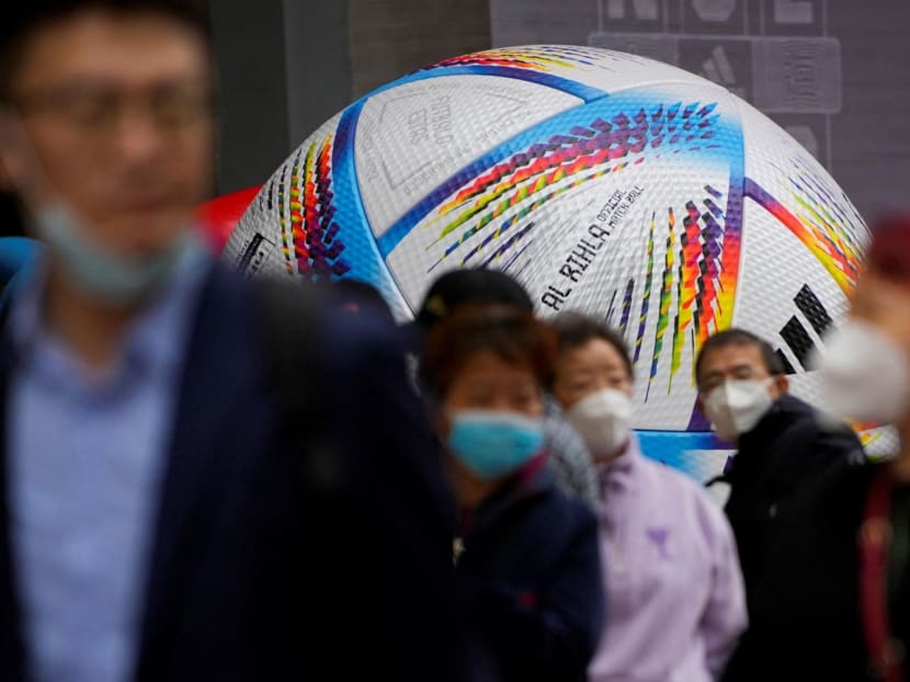 People wearing face masks walk by the giant model of Fifa World Cup Qatar 2022 match ball, amid the Covid-19 outbreak in Shanghai, China on Nov 23, 2022. 
