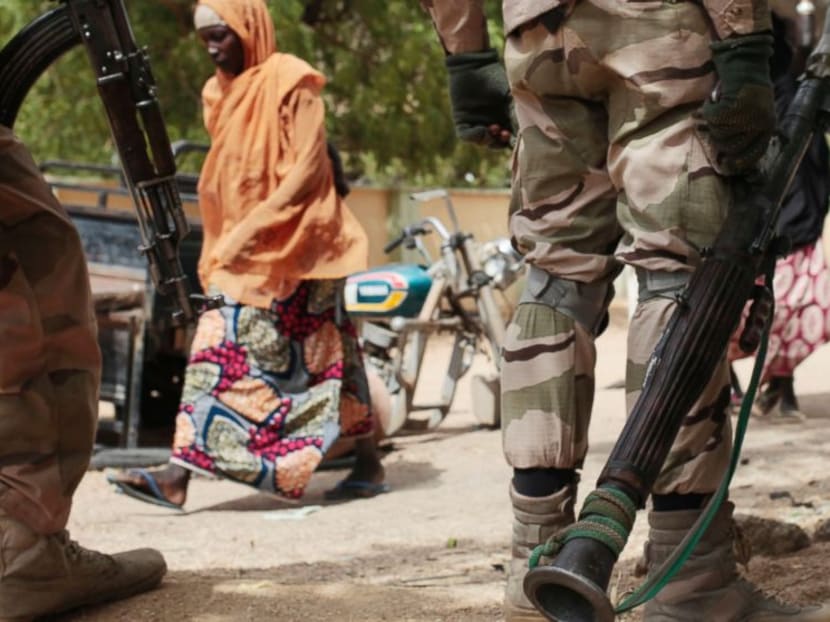 In this photo taken on Wednesday, April 8, 2015, a woman walks past Nigerian soldiers at a checkpoint in Gwoza, Nigeria, a town newly liberated from Boko Haram. Photo: AP
