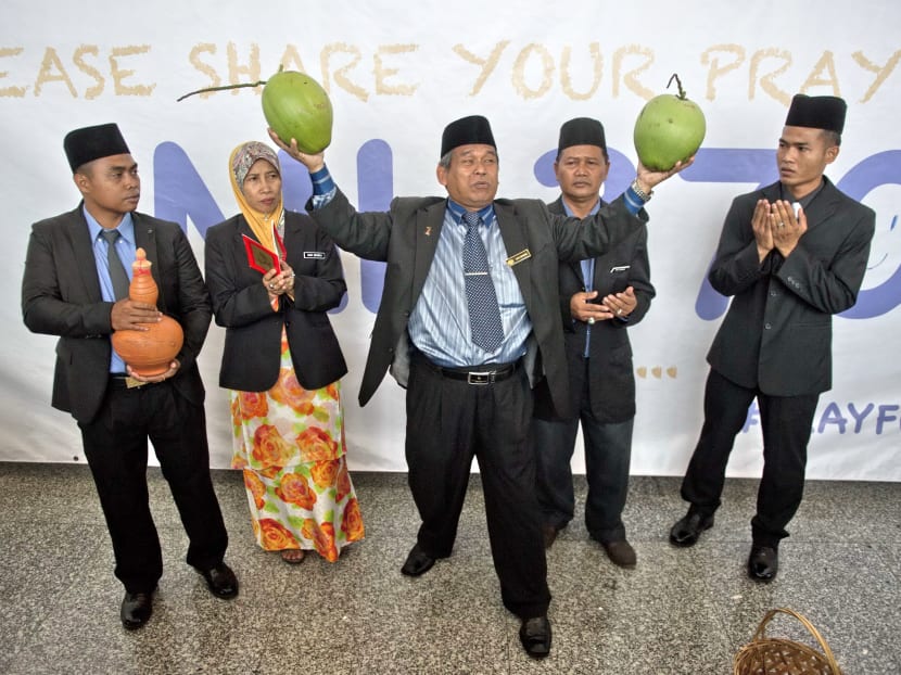 Ibrahim Mat Zin (C) holds two coconuts as him and his assistants offer to locate the missing Malaysia Airlines flight 370 plane using a spiritual method and prayer at the Kuala Lumpur International Airport (KLIA) in Sepang on March 12, 2014. AFP file photo