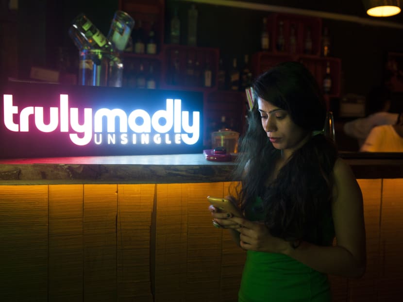 In this June 11, 2015 photo, an Indian girl checks her mobile phone at a party hosted by TrulyMadly, one of India’s online dating apps in Gurgaon, India. Photo: AP