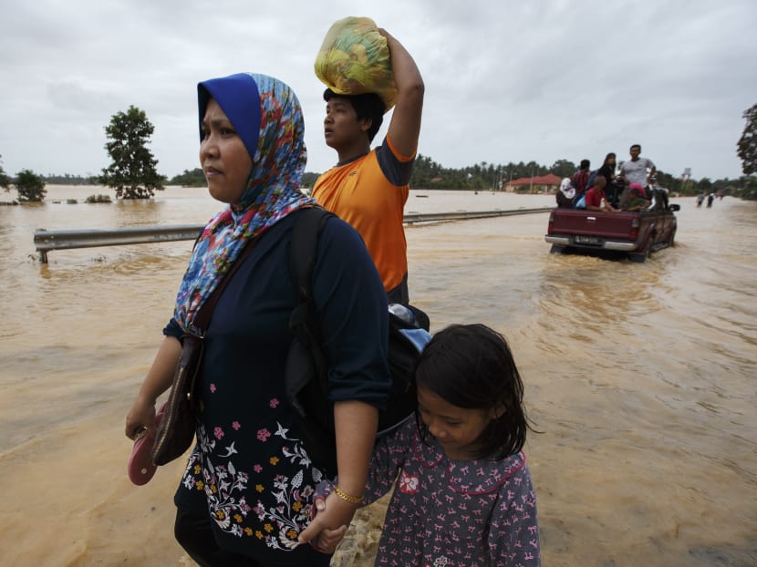 People carry their belongings as they evacuate through a flooded street, on the outskirts of Kota Bharu in Kelantan, Dec 29, 2014.