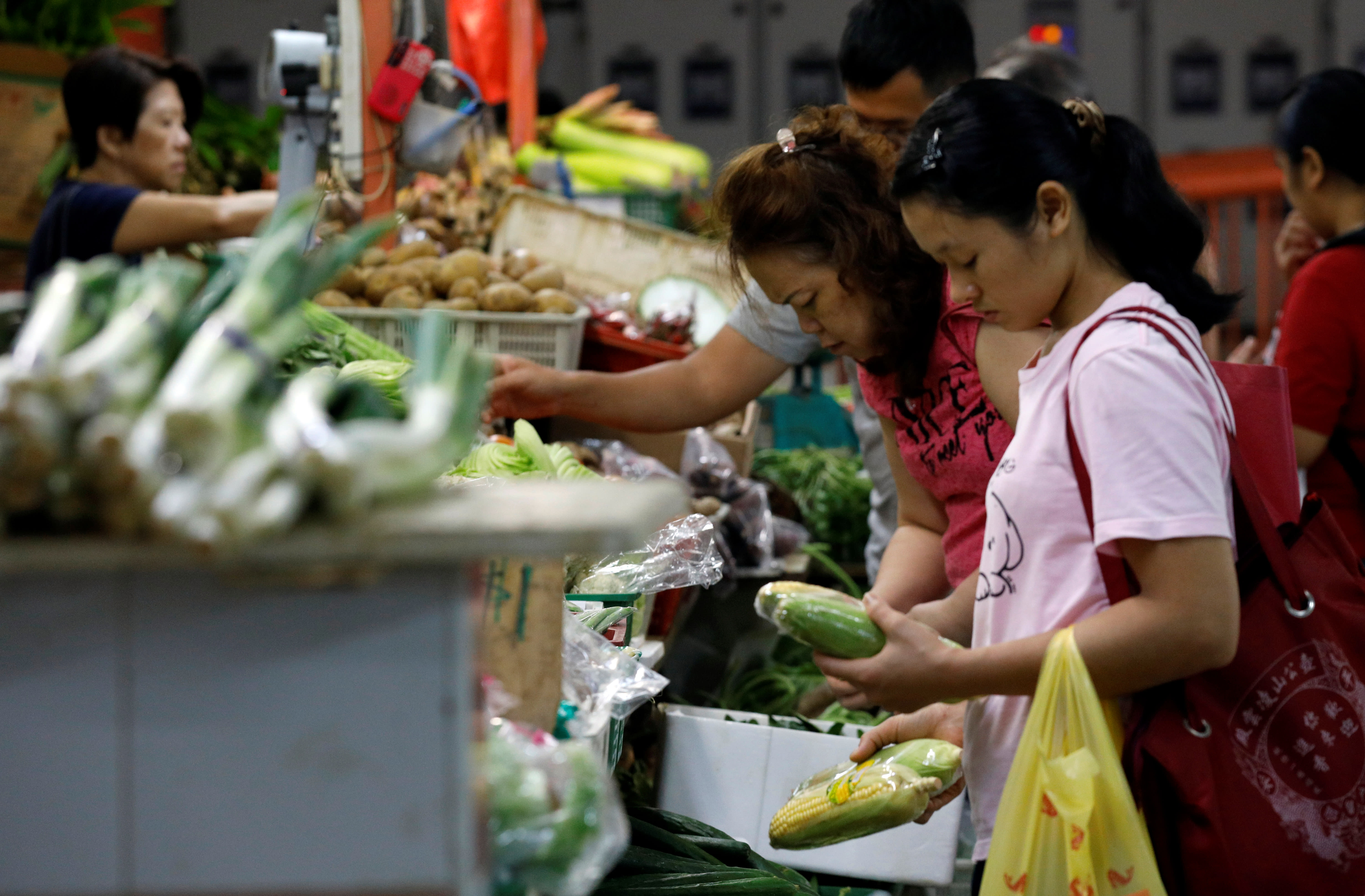 People shop for vegetables at a wet market in Singapore. People shop for vegetables at a wet market in Singapore.