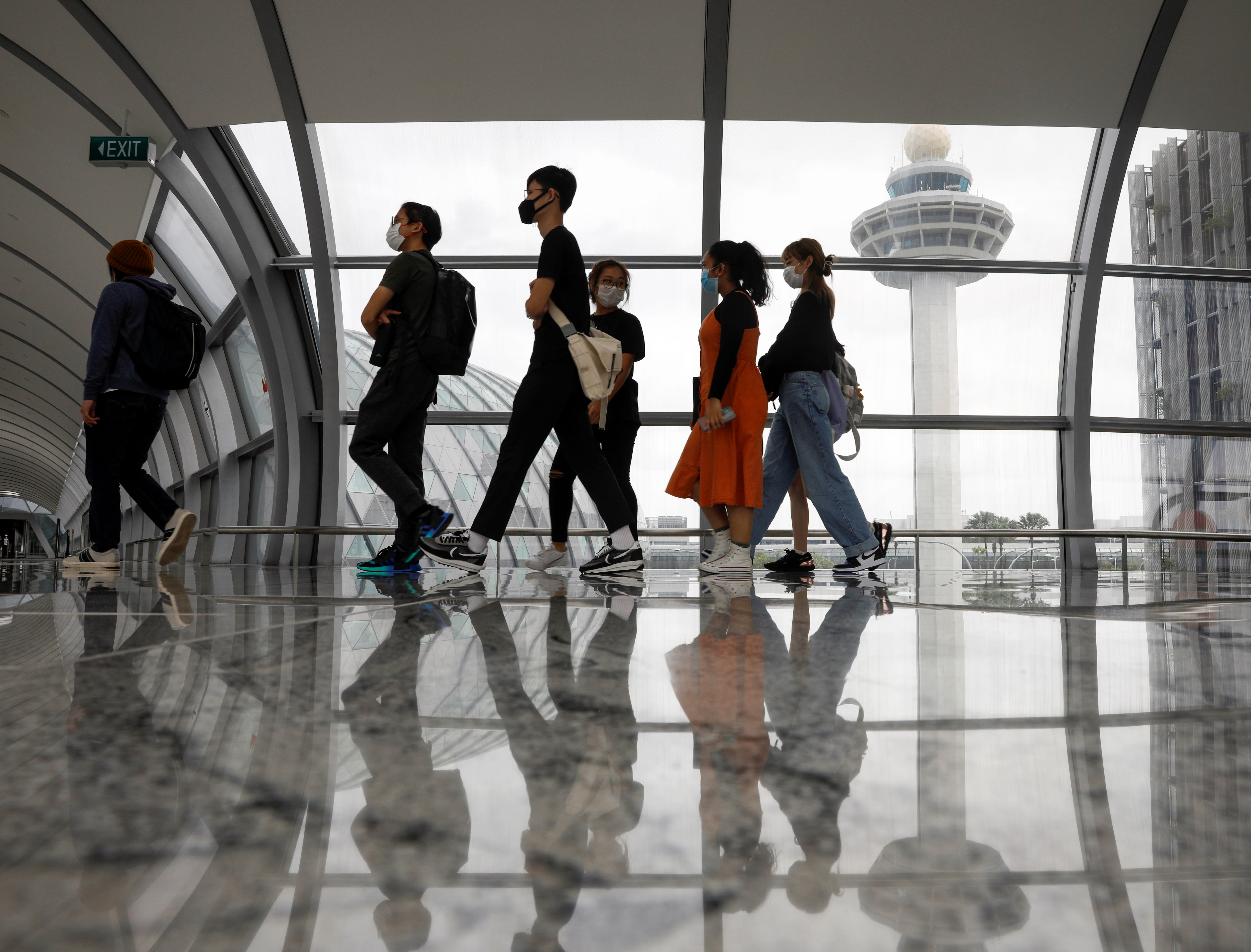 People passing the control tower of Changi Airport.