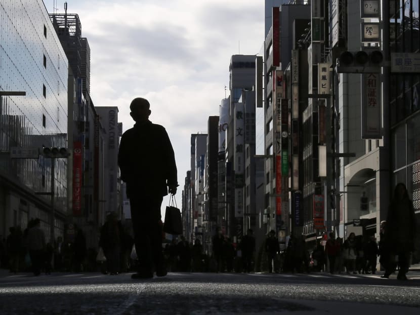 A man holding a shopping bag walks on a street at Tokyo's Ginza shopping district on Nov 16, 2014. Japan's economy unexpectedly shrank an annualised 1.6 per cent in July-September after a severe contraction in the previous quarter. Photo: Reuters