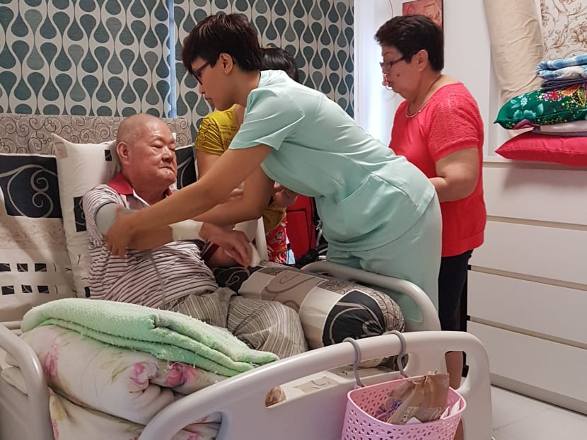 Ms Haslinda Barman, Patient Navigator from Singapore General Hospital, teaching Mdm Sim Poh Cheng, 61, who is the wife and main caregiver of Mr Choo Kim Sua, how to measure Mr Choo's blood pressure. Photo: SingHelath